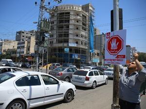 A Palestinian man hangs on May 22, 2017 in Gaza City a traffic sing with Arabic writing on reading "stand with our prisoners'' in solidarity with Palestinian hunger-striking prisoners in Israeli jails. (AFP/Mohammed Abed)