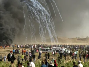 Palestinian protesters run for cover after Israeli forces launched tear gas canisters during a demonstration along the border on June 22, 2018. (MAHMUD HAMS/AFP)
