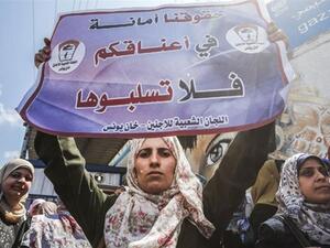 A woman holds a sign reading 'We trust you with our rights, please do not rob them' during a demonstration by UNRWA employees. (Mahmud Hams/AFP)
