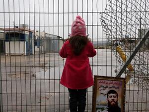 Maali, daughter of jailed Islamic Jihad spokesman Khader Adnan, stands next to a picture of her father outside a prison. (AFP/Abbas Momani)