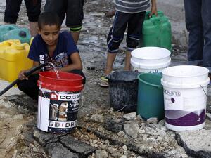 Palestinians collect water from a broken pipe (Mohammed Abed/AFP)