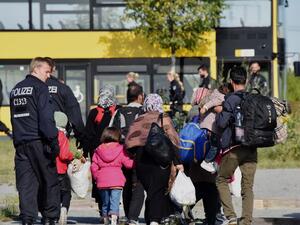 Police officers accompany migrants to a bus after they arrive at the railway station in Schoenefeld near Berlin, eastern Germany, on Sept. 8, 2015. (AFP/Bernd Settink)