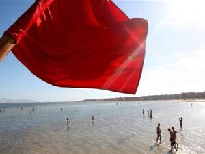 A red flag serving as a warning of shark sightings flutters over tourists enjoying a day on the beach in the Red Sea resort of Sharm el-Sheikh on December 8, 2010