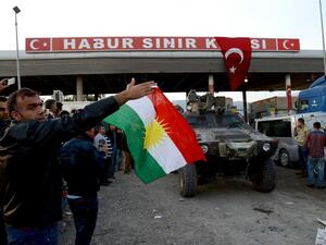 A Turkish Kurd waves a Kurdish flag at Iraqi peshmerga forces as they enter Turkey on the way to join the fight against ISIL in Syria's Kobani. (AFP/FIle)