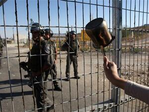A protester waves a coffee pot at Israeli guards outside Ofer Prison. (AFP/File)