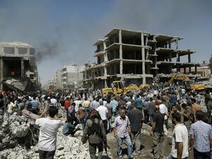 Syrians gather around one of the bombed buildings in Qamishli on July 27, 2016. (AFP/Delil Souleiman)
