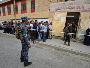 Members of the Iraqi security forces stand guard as people queue in front of a polling station in the Wadi Hajar district of Mosul on May 12 /AFP