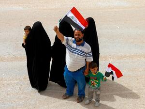 An Iraqi man and a child wave the national flag in the central holy city of Najaf on May 12, 2018 as the country votes in the first parliamentary election since declaring victory over ISIS. (AFP/File Photo)