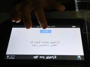 A voting official checks the message on the voting machine, which reads in Arabic "Voting time is over, the station is now closed" /AFP