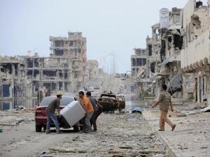 This file photo taken on October 24, 2011 shows Libyans load their belongings into a car in a destroyed street in Sirte. (AFP/File)