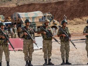 Turkish soldiers stand near armored vehicles near the Turkey-Syria border. (Ilyas Akengin/AFP)