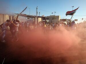 Sadrist protesters outside of Baghdad's Green Zone react to canisters of tear gas. (AFP/Ahmad Al-Rubaye)