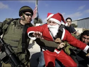 An Israeli soldier tackles a Palestinian protester dressed as Santa Claus or Father Christmas during at a protest against Israel’s separation barrier in the village of Umm Salamunah near the biblical West Bank town of Bethlehem. Israeli guards beat five demonstrators during the protest on Friday, organisers said.
Dec. 23, 2007 (AFP/Musa al-Shaer)