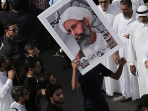 Protesters hold a sign featuring Sheikh Nimr al-Nimr. (Twitter)