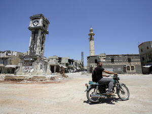  A Syrian man rides his motorbike past the Sunni Grand mosque in the city of Qusayr, in Syria's central Homs province. (AFP/JOSEPH EID)