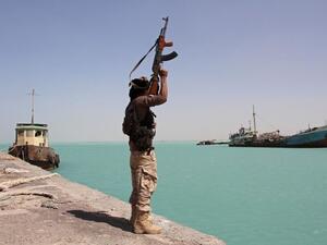 a member of the pro-government forces raises his weapon in the port of the western Yemeni coastal town of Mokha. (AFP/ File)