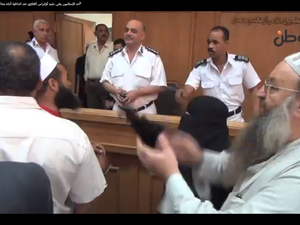 A fully covered woman pounds the desk of the police while leading a chant in Egypt. (screen grab from YouTube)