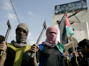 Palestinian students in checkered keffiyehs holding axes. (photo: AFP) 