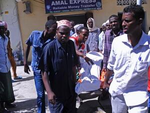 People carry the body of a civilian killed in the al-Shabaab attack on the presidential palace on February 25, 2016. (AFP/Mohamed Abdiwahab)