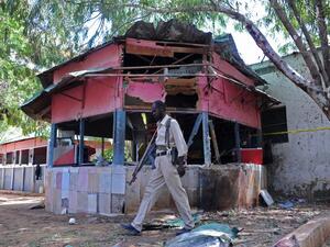 A Somali policeman walks at the scene of an explosion at the Village Restaurant in Mogadishu, on January 2, 2016. (AFP/Mohamed Abdiwahab)