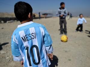 Afghan boy five-year-old Murtaza Ahmadi (C), a young Lionel Messi fan, plays football as he wears a donated and signed shirt by Messi on a field in Kabul on February 26, 2016. Argentine football star Lionel Messi has sent not one, but two jerseys to the five-year-old Afghan boy who became an Internet sensation last month when he was pictured wearing a plastic bag with "Messi" scrawled on it in marker pen. AFP. AFP PHOTO/WAKIL KOHSAR
WAKIL KOHSAR / AFP