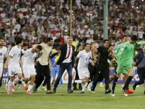 لاعبو منتخب إيران والمدرب كارلوس كيروش (وسط) يحتفلون بالتأهل