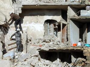 Rescuers climb on the rubble of a destroyed building following an airstrike in the northern Syrian city of Aleppo on December 24, 2013. Syrian warplanes have killed more than 330 people in a nine-day bombing campaign. [AFP]