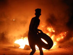A resident of Basra holds up a tire outside the burning Iranian Consulate (AFP/FILE)