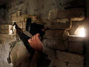 A member of the Islamic State of Iraq and the Levant carries his weapon as he looks through a hole in a wall in Sheikh Saeed neighbourhood December 4, 2013. [AFP]
