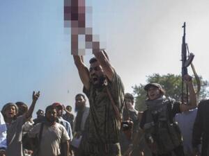 An ISIS soldier, in a recent execution, holds the severed head of a militant. [LeJournal]