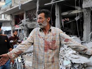 A Syrian man holds up his hands after Russian air strike in the district of Jisr Al-Shughur in the Idlib province (AFP/FILE)