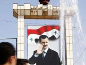 شبان يمرون امام صورة كبيرة لبشار الاسد في درعا