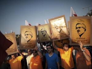 Demonstrators outside the Bahraini capital Manama hold up posters of jailed secular opposition leader Ibrahim Sharif who was released Friday after four years in prison.  (AFP/File)