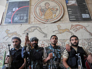 Syrian opposition fighters pose in front of a mosaic at the now heavily damaged museum in the rebel-held town of Maaret al-Numan.  (AFP/Bulent Kilic)
