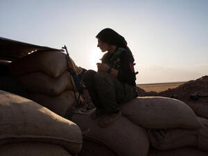 A fighter of the Kurdish of the Kurdish Women's Defense Units (YPJ) sits on sand bags as she holds a position on the front line in Syria. (Image credit: AFP) 