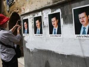 سائحة تلتقط صورا لجدار الصقت عليه صور لبشار الاسد في دمشق