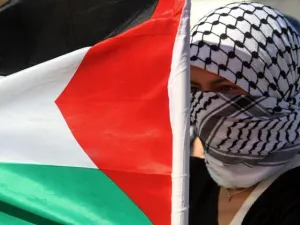 فلسطينية ترفع العلم الوطني بالقرب من حاجز اسرائيلي خلال تظاهرة احتجاج ضد العدوان على غزة في نابلس بالضفة الغربية/أ.ف.ب