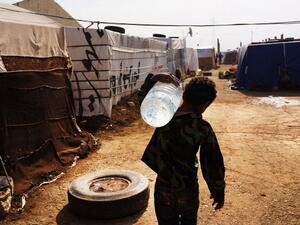 A displaced Syrian child walks through a camp with a jug of water in a makeshift camp for Syrian refugees only miles from the border with Syria in the Bekaa Valley on November 12, 2013 in Majdal Anjar, Lebanon. [Spencer Platt/ Getty Images]