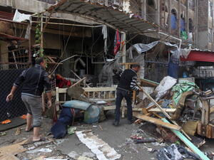 Iraqi men clean the rubble at the site of a blast that took place the previous day outside a cafe in Baghdad's Bayaa neighborhood on November 21, 2013. [Getty Images]
