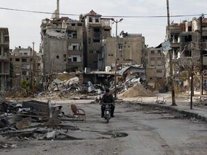 A man drives his motorbike past damaged buildings on February 10, 2016 in Harasta, east of the Syrian capital Damascus. (AFP/Abdulmonam Eassa)