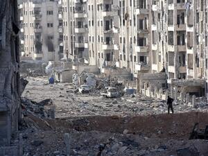 A member of the Syrian pro-government forces stands amid heavily damaged buildings in Aleppo's 1070 district on November 8, 2016, after troops seized it from rebel fighters. (AFP/Georges Ourfalian)