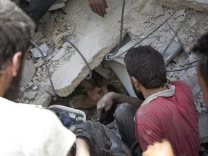 Syrian civil defence volunteers, known as the White Helmets, dig out a young boy trapped under the rubble of destroyed buildings following reported air strikes on the rebel-held neighbourhood of Al-Mashhad in the northern city of Aleppo, on July 25, 2016. (AFP/Karam al-Masri)