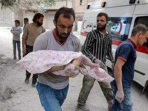 A Syrian man carries the body of an infant retrieved from under the rubble of a building following a reported airstrike on September 23, 2016, on the al-Muasalat area in the northern Syrian city of Aleppo. (AFP/Thaer Mohammed)
