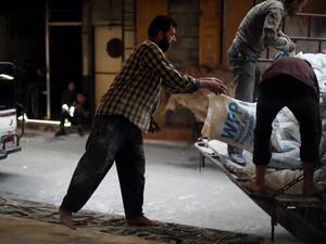 Syrian men load aid parcels provided by the UN World Food Program (WFP) and the Syrian Arab Red Crescent into a truck for food distribution on May 11, 2016, in the rebel-held village of Saqba, nearl Damascus. (AFP/Amer al-Mohibany)