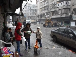 Syrian children gather around a fire as the Syrian government starts to clean up areas formerly held by opposition forces in Aleppo on December 27, 2016, in the Shaar district. (AFP/George Ourfalian)