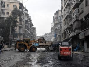 A tractor removes rubble as the Syrian government starts to clean up areas formerly held by opposition forces in the northern city of Aleppo on December 27, 2016, in the Shaar district. (AFP/George Ourfalian)