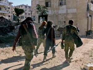 Rebel fighters walk down a street west of the northern Syrian city of Aleppo on December 9, 2016. (AFP/Thaer Mohammed)