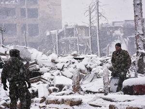 Syrian pro-government forces walk as snow falls in Aleppo on December 21, 2016. (AFP/George Ourfalian)