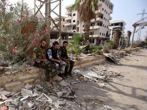 Syrian army soldiers gather in a street in the government-controlled part of the besieged town of Daraya on August 26, 2016, as thousands of rebel fighters and civilians prepared to evacuate under an accord struck a day earlier. (AFP/Youssef Karwashan)