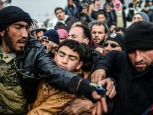 Syrian refugees jostle each other near the Turkish border crossing on February 6, 2016. (AFP/File)
